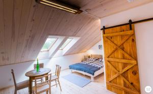 sypialnia z łóżkiem, stołem i drewnianymi drzwiami w obiekcie Siedlisko Sobibór w mieście Sobibór