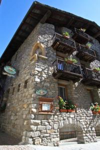 un edificio de piedra con macetas y balcones. en Hotel Dolonne en Courmayeur