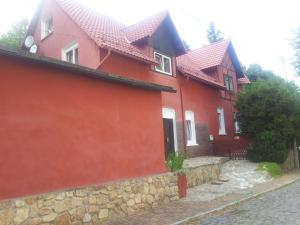 a red house with a stone wall at Pokój gościnny ROYAL in Świeradów-Zdrój