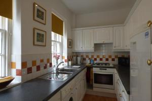 a kitchen with white cabinets and a sink and a stove at 1 HAVANNAH COURT in Kelso