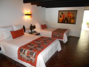a hotel room with two beds and a painting on the wall at Hotel Hacienda Taboada (Aguas Termales) in San Miguel de Allende