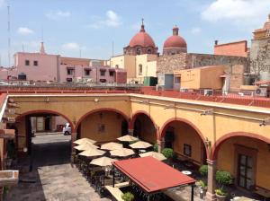 um pátio exterior com mesas e guarda-sóis num edifício em Hotel Quinta Santiago em Querétaro