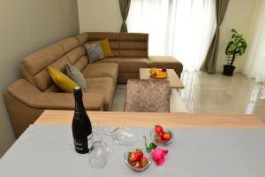 una botella de vino y dos tazones de fruta en una mesa en Ralux apartman Tivat, en Tivat