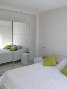 a white bedroom with a bed and a mirror at Appartement vacances cannes in Cannes