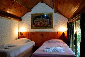 two beds in a room with a painting on the wall at Spa e Hotel Fazenda Gaura Mandir in Teresópolis