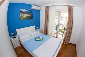 a bedroom with a white bed with a blue wall at Villa DiEden in Budva