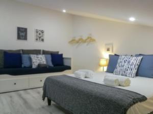 a bedroom with a bed with blue pillows and a couch at BmyT - The Villa in Lisbon