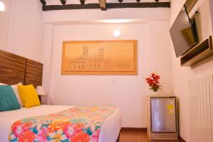 a bedroom with a bed and a painting on the wall at Hotel Cacique Real in Zipaquirá
