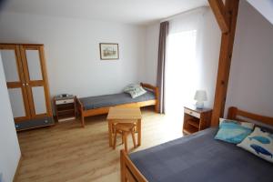 a bedroom with two beds and a table in it at Willa Nauta in Dębki