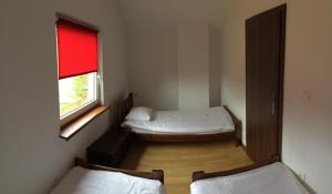a small room with two beds and a window at Domki Magnolia in Dźwirzyno