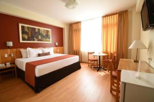 una camera d'albergo con un letto e una televisione di Qorianka Hotel a Lima Altre 37 foto