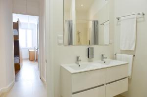 une salle de bain blanche avec deux lavabos et un miroir dans l'établissement Internacional Azores Boutique, à Horta 82 autres photos