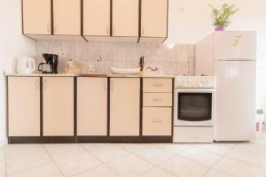 a kitchen with white cabinets and a white refrigerator at Apartman Deni in Peroj