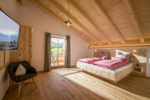 een slaapkamer met een bed, een stoel en een raam bij Lainthalerhof in Oberaudorf