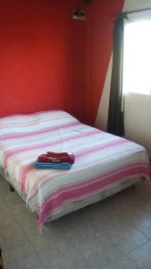 ein Bett in einem Zimmer mit einer roten Wand in der Unterkunft La Palmera escondida in Colón