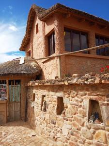 une maison en pierre avec un toit de paille dans l'établissement Hostal Qhana Pacha, à Isla de la Luna