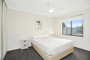 a white bedroom with a bed and a window at Bayside in Aldinga Beach