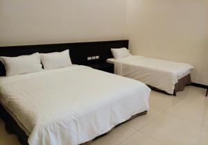 two beds with white sheets in a room at Really good home in Taitung City