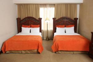 duas camas com lençóis laranja num quarto de hotel em Hotel Gran Mediterraneo em San Pedro Sula