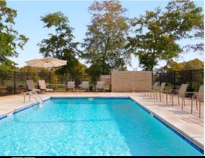 una piscina con sillas y sombrilla en Microtel Inn & Suites by Wyndham Ozark, en Ozark