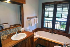 a bathroom with a tub and a sink and a mirror at Bridgefield Guest House in Margaret River Town