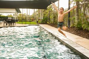 a young boy jumping into a swimming pool at San Marino by the Sea Apartments in Marcoola