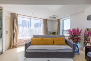 sala de estar con sofá y almohadas amarillas en Dalian Xiuzhu Mansion Apartment en Dalian
