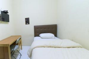 ein kleines Schlafzimmer mit einem Bett und einem Schreibtisch in der Unterkunft Guest House Samarinda in Samarinda