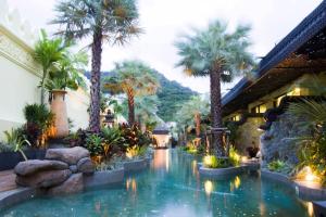 a resort with palm trees and a swimming pool at Sawasdee Village in Kata Beach