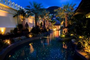 a pool in a house with palm trees and lights at Sawasdee Village in Kata Beach