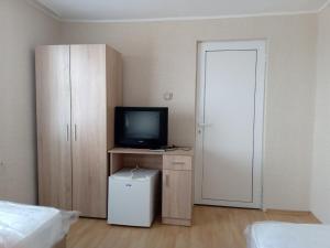 ブルガスにあるPrometeiのベッド、テレビ、ドアが備わる客室です。