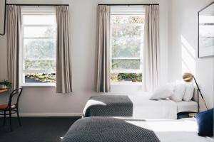 a bedroom with two beds and two windows at Naughtons Hotel in Melbourne