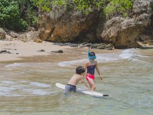 zwei Kinder spielen auf einem Surfbrett im Wasser in der Unterkunft Hideout Okinawa Uruma in Uruma