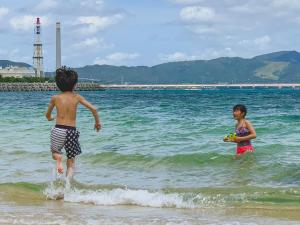 zwei Kinder spielen im Wasser am Strand in der Unterkunft Hideout Okinawa Uruma in Uruma