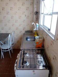 a kitchen with a stove and a sink at Apto Residencial Fernanda - PRAIA GUILHERMINA - Com Wi-Fi in Praia Grande