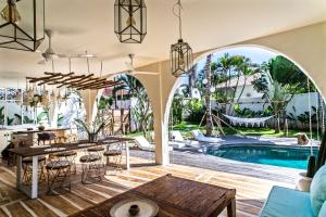 a villa with a pool and a dining room with tables and chairs at La Payesa in Canggu