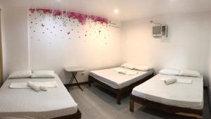 une chambre avec trois lits et un tableau mural dans l'établissement Seabreeze Beach Lodge, à Nasugbu
