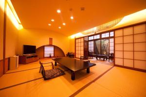 a living room with a table and a tv at Kappo Ryokan Kannawa Bettei in Beppu