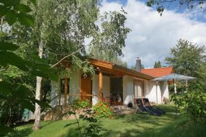 une petite maison blanche avec une terrasse couverte et des chaises dans l'établissement Harzer Feriengarten 5*****, à Bad Suderode