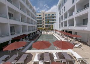 una piscina con sillas y sombrillas junto a un edificio en Kokkinos Boutique Hotel, en Protaras