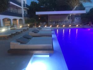 a pool with lounge chairs and a hotel at night at Danae Hotel in Egina