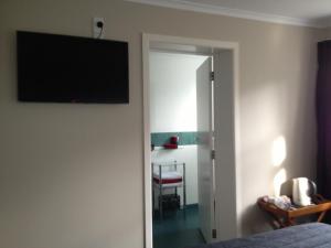 1 dormitorio con TV de pantalla plana en la pared en Lovett Lodge, en Invercargill