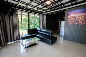 a living room with a black leather couch and a table at Blue Moon Design House in Ko Samed