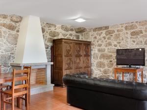 a living room with a black leather couch and a fireplace at Quinta do Bárrio - Manor Guest House in Terras de Bouro