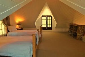 a attic bedroom with two beds and a window at Dalmore Guest Farm in Bergville