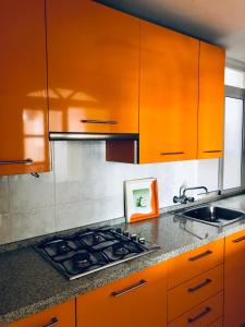 - une cuisine avec des armoires orange, une cuisinière et un évier dans l'établissement Beautiful modern apartment 100m from the sea, à Fuengirola