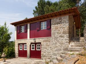 a small stone house with red doors and a fire hydrant at Quinta do Bárrio - Manor Guest House in Terras de Bouro