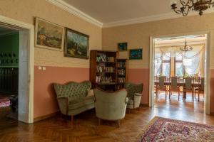 a living room with two chairs and a book shelf at Pałac Pozorty in Pozorty