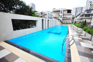 - une grande piscine bleue sur le côté d'un bâtiment dans l'établissement Parinda Hotel, à Bangkok