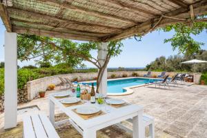 a white table under a pergola next to a swimming pool at Finca Binicalaf Vell in Cala'n Porter
